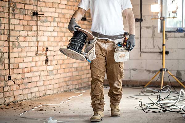 electrician holding spool of cables and wires